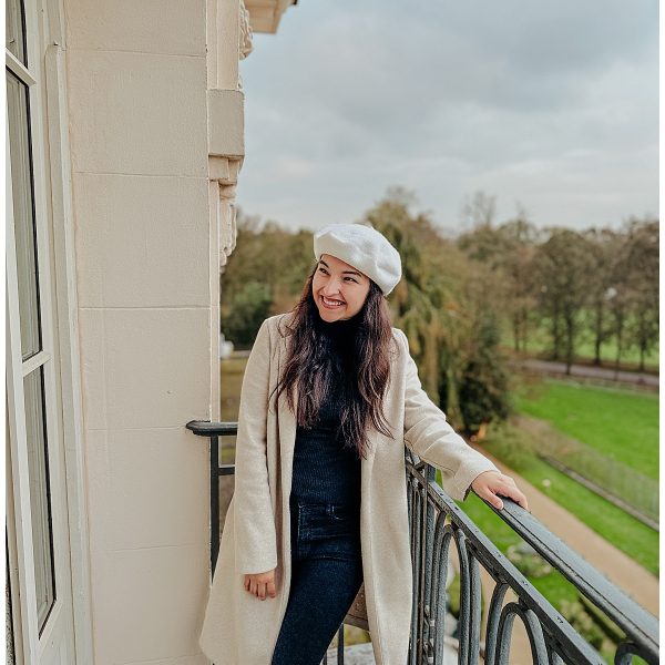 Woman standing on a balcony at Waldorf Astoria Trianon Palace near Versailles, enjoying the serene view of the surrounding gardens.